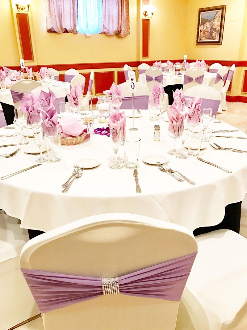 Round table set for many people with purple and white chairs