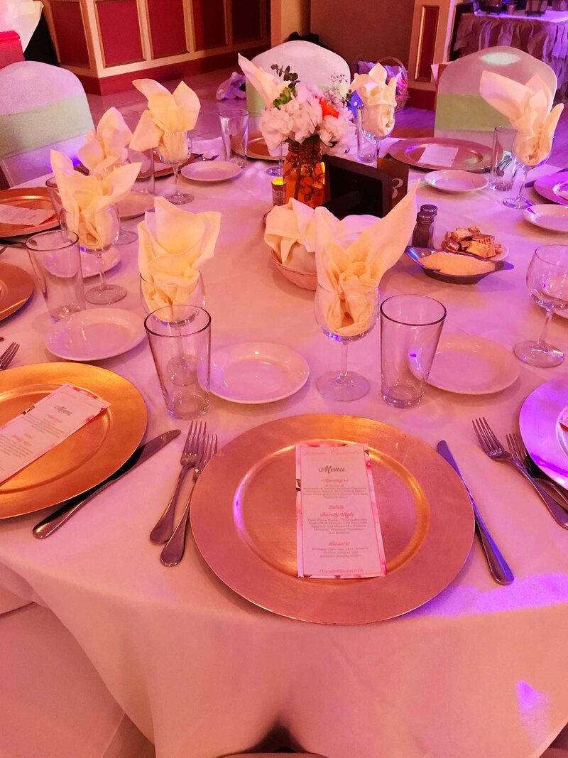 Table set for many guests with gold plates and white napkins