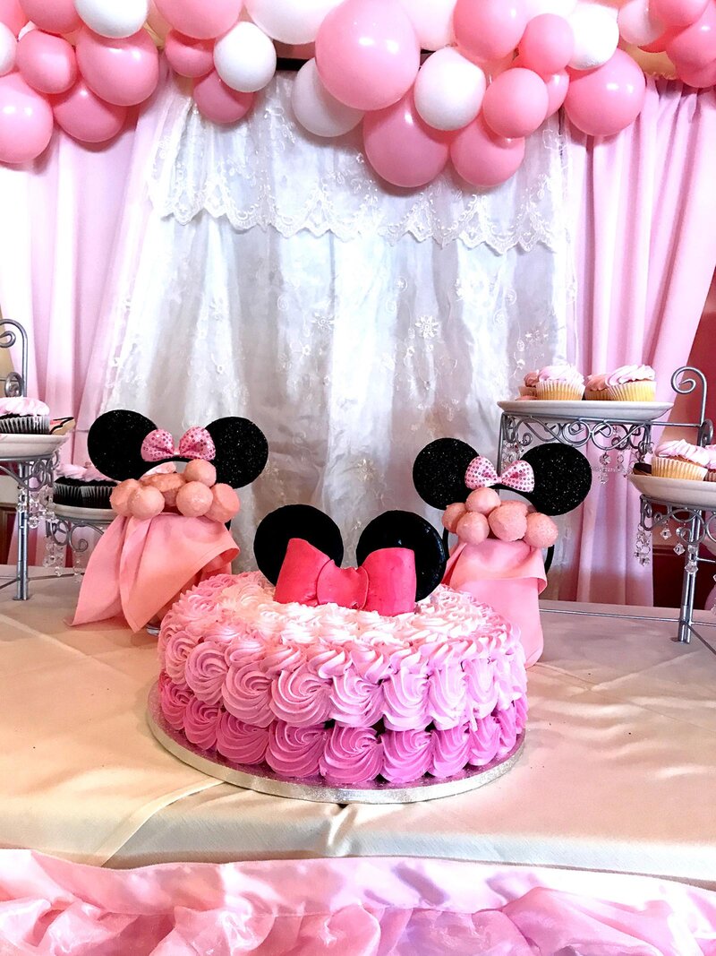 Dessert table with pink cake and cupcakes